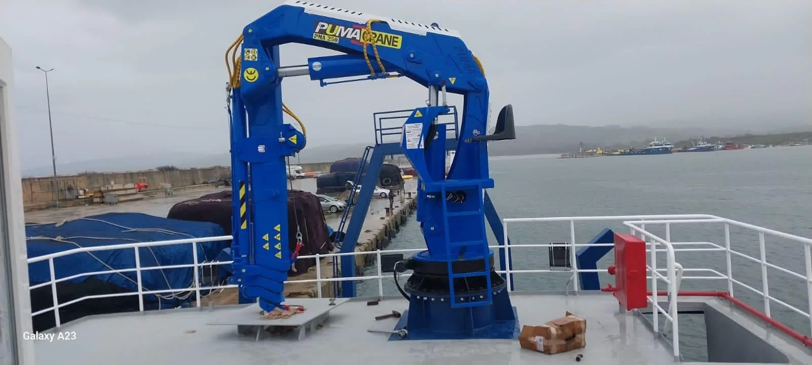 Blue folding marine crane installed on a vessel deck