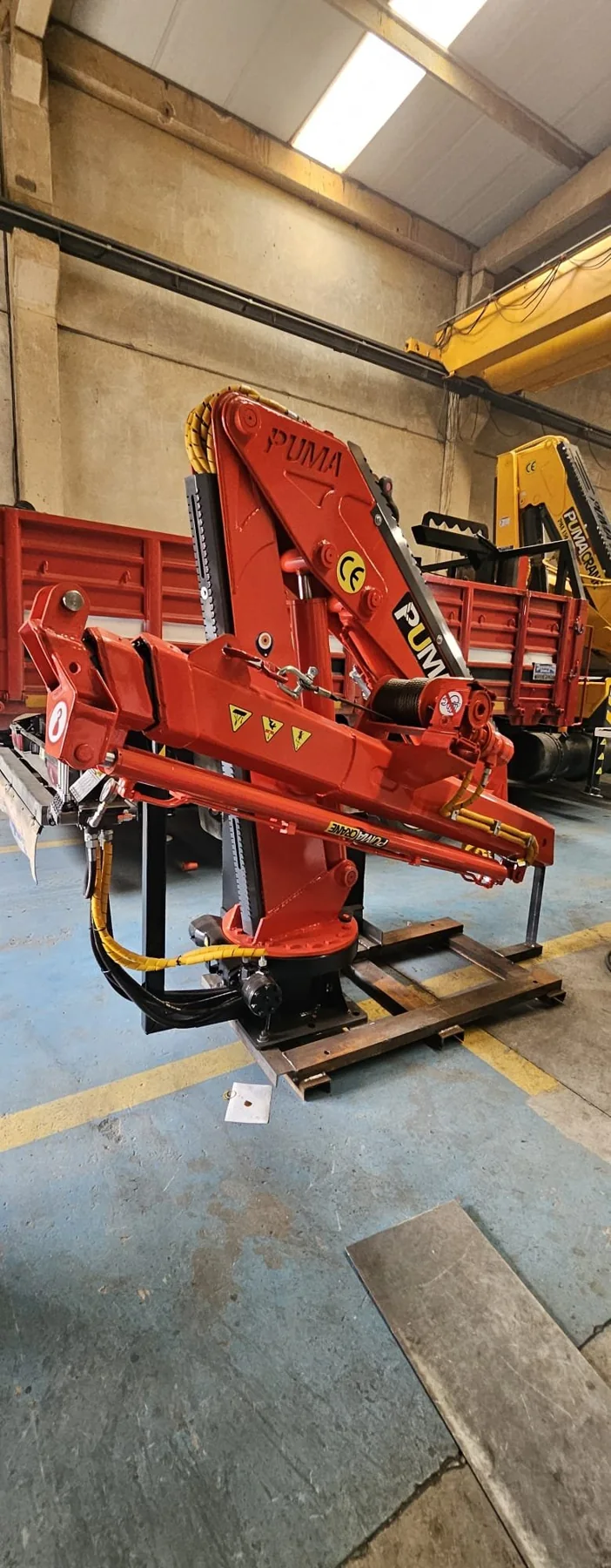 Red folding marine crane prepared in a manufacturer workshop