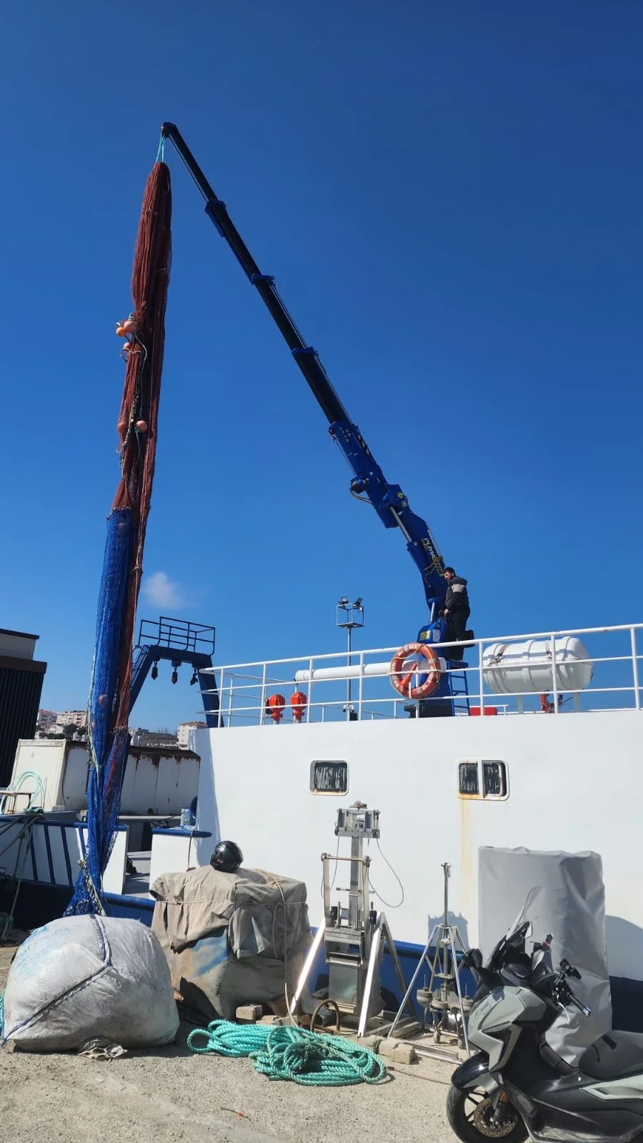 Red long-boom marine crane installed on a fishing-vessel deck