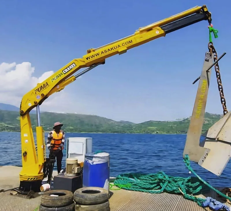 Yellow marine deck crane operating on a workboat